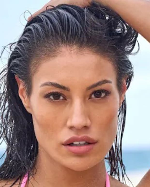 Ashley Callingbull poses in front of the ocean with her hand on her head.